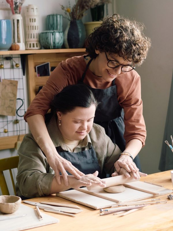 Artisan And Girl With Disability Rolling Out Clay